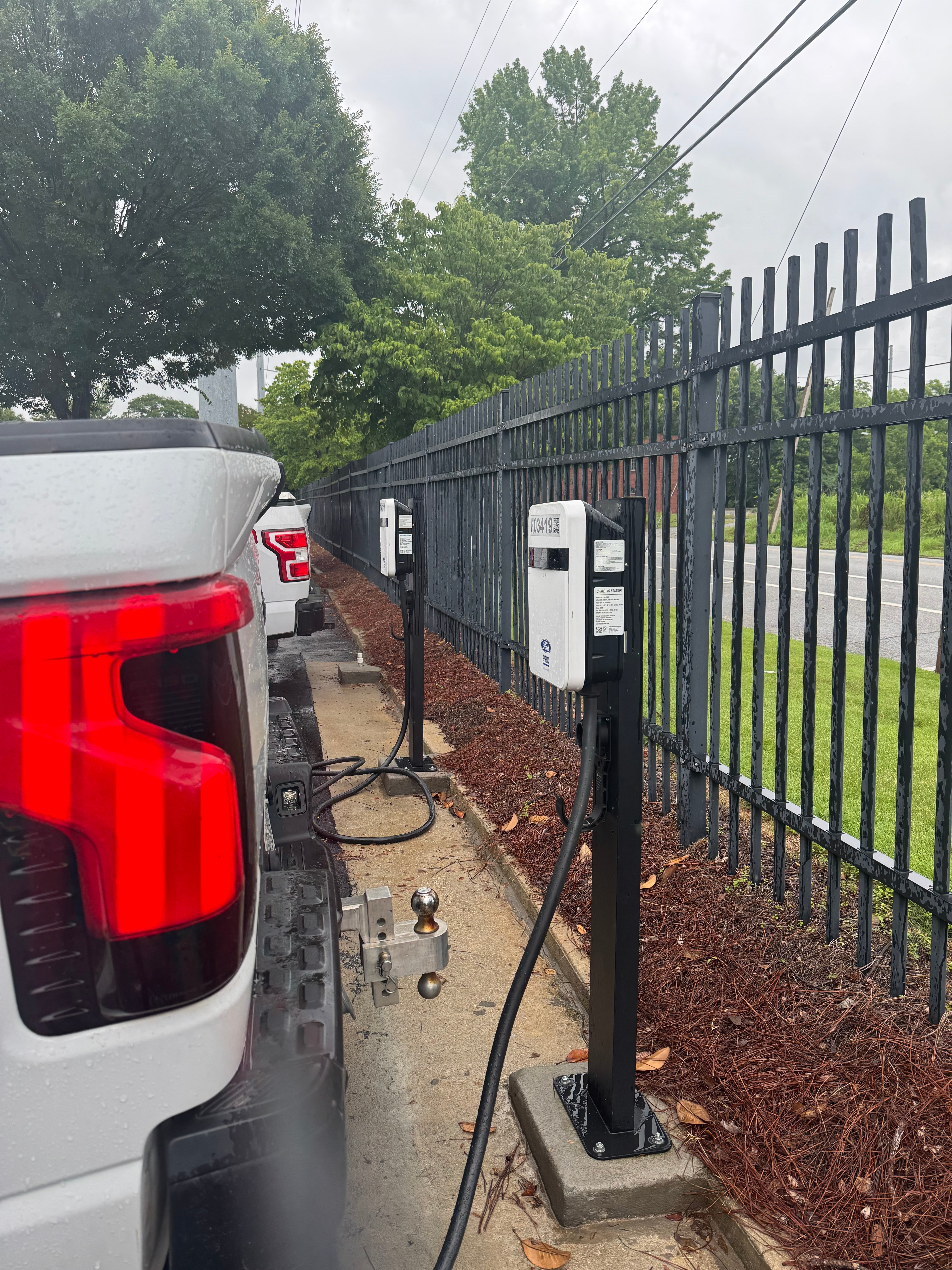 The back of a white truck is shown backed up to a Ford Pro charging station